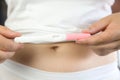 Young women wearing white underwear with hand holding blank pregnancy test and belly