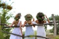 Young women wearing wreaths made of beautiful flowers near wooden fence, back view