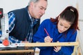 Young woman working at carpenter shop with teacher Royalty Free Stock Photo