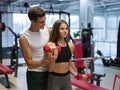 A woman doing exercises with dumbbells on a gym background. A personal trainer helping a client on a fitness club. Royalty Free Stock Photo