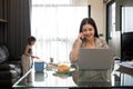 The young woman works from home, raises her daughter, and discusses work with co-workers on the phone and online. Royalty Free Stock Photo