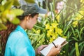 Young women write note among orchid garden. Colorful orchids, Orchid flower bloom Royalty Free Stock Photo