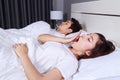 Woman yawning and her husband sleeping on bed Royalty Free Stock Photo