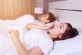 Woman yawning and her husband sleeping on bed Royalty Free Stock Photo