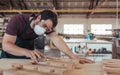 Young woodworker skillfully sanding furniture alone in his workshop