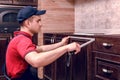 A young worker is assembling modern wooden kitchen furniture