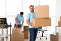 Young worker with cardboard and his colleague in office. Moving service