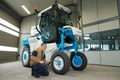 Young worker checksing vineyard tractor in garage