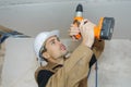 Young worker drilling ceiling