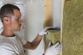 Young worker in goggles and white gloves insulating rock wool insulation staff in wooden frame for future walls for cold barrier. Royalty Free Stock Photo