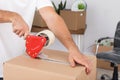 Young worker packing cardboard box in room. Moving service Royalty Free Stock Photo