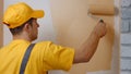 Young worker painting wall indoors. Royalty Free Stock Photo