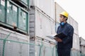 Young worker in protective work wear examining cargo in a shipping yard