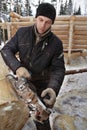 Young worker removes bark from log using electric planer.