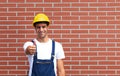 Young worker showing tumb up in front of a brick wall