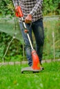 Young worker using a lawn trimmer mower cutting grass in a blurred nature background Royalty Free Stock Photo