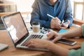 Young worker writing on notebbok while working with colleague