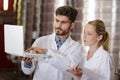 young workers wearing labcoats holding white laptop