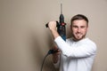 Young working man with rotary hammer on beige background Royalty Free Stock Photo