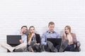 Young working people sitting by the wall