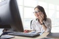 Young working woman talking to phone with watching on computer o