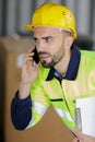 young workman holding clipboard and talking on telephone