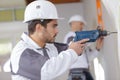 Young workman using drill on indoor wall