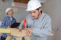 Young workman using handsaw senior colleague assessing site Royalty Free Stock Photo