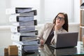 Worried Businesswoman Looking At Folders Stack