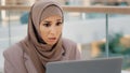 Young worried stressed arab businesswoman in hijab looking at laptop screen feeling shocked annoyed due to problem Royalty Free Stock Photo