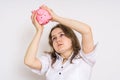 Young worried woman is looking on empty piggy money bank