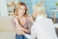 Young worried woman sitting and listening to her wise senior grandmother