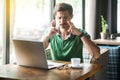 Young worry hopeful businessman in green t-shirt sitting with closed eyes and crossed fingers and hope to win