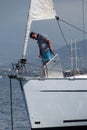 A young yachtsman anchors the anchor by an electric winch standing on the bow of a sailing yacht. Yacht school in practice. The ch