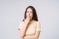 Young yawning asian woman winner with long hair in yellow shirt on grey background Royalty Free Stock Photo