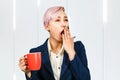 Young yawning girl office worker holds cup of a coffee