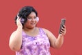 Young 20-year-old brunette and fat woman uses headphones and cell phone to listen to music, playlists, podcasts, audiobooks