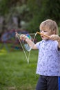 Young, 4 year old preschool boy with a grey shirt and blond hair, blowing bubbles in the yard Royalty Free Stock Photo