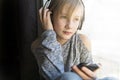 Young 10 years woman listening music close to the window