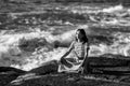 Young yoga woman meditates in the lotus position, sitting on the rocks on the ocean shore. Royalty Free Stock Photo