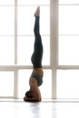 Young yogi attractive woman practicing yoga, doing headstand