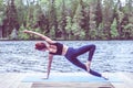 Young yogi girl practicing yoga, Camatkarasana, Wild Thing or Flip-the-Dog posture on the lake. Concept of healthy life and