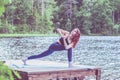 Young yogi girl practicing yoga, Parsvakonasana, side angle pose, on the lake. Concept of healthy life and natural balance