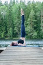 yogi  girl  practicing yoga, standing in Salamba Sarvangasana exercise, supported Shoulder stand pose on the lake.  Concept Royalty Free Stock Photo