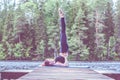 Young yogi  girl  practicing yoga, standing in Salamba Sarvangasana exercise, supported Shoulder stand pose on the lake.  Concept Royalty Free Stock Photo