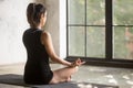 Young yogi woman in Easy Seat pose, window background