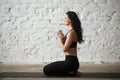 Young yogi woman in seiza pose with namaste, loft background