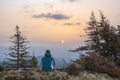 A young youth in headphones watches the sunrise in the mountains with a cup of tea, a sonception, a trip, a hike, a rest, solitude