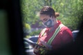 Young youthful fast food worker working at Chick-fil-a drive through amidst cars take orders with tablet