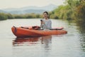 Younger asian woman with smartphone in hand sitting in sea kayak toothy smiling with happiness Royalty Free Stock Photo